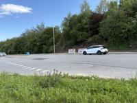 Udkørsel fra Tonne kjærsvej. Der kan være meget trafik i myldretiden. Cyklister som skal svinge til venstre kommer i konflikt med biler som svinger til højre. Rampen til cykelstien på modsatte side befinder sig i lige linje gennem den grå bil. 